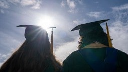 grad couple silhouetted against bright sun