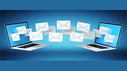 two laptops with email envelopes floating in between