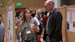 student discussing research poster with professor