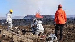 Scientists collecting volcanic rock during a July 2023 eruption