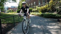 a person rides a white bicycle near the science buildings on the UO campus