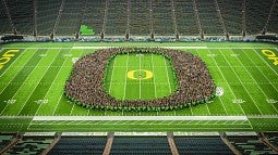 The class of 2027 photo with people standing in the shape of the UO logo on the field of Autzen Stadium.