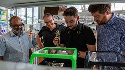 Researchers Ramesh Jasti, Paul Dalton, Patrick Hall and Harrison Reid shine a UV light onto one of the scaffolds made with nanohoops