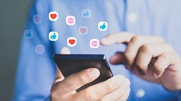 Person using cellphone with social media icons floating around