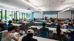 A professor teaches a group of students in a large classroom