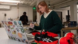 Lulu West working at a laptop, shoe samples nearby