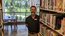 Michael Brown stands next to UO Portland Library bookshelves