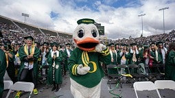 The Duck surrounded by graduates at a UO commencement ceremony