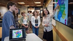 A teacher looking at wall map with students
