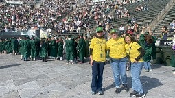 UO employees in yellow volunteer shirts assist at the procession at the university's commencement ceremony