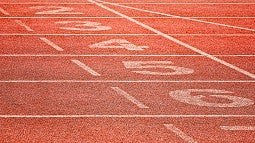 A low view of a red cinder track and field surface