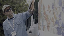 Presenter gestures toward a map depicting the geology of Portland, Oregon.