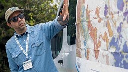 Man gesturing at map taped to a van outdoors