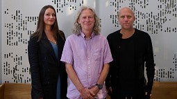 Three people standing in front of walls marked with fractal patterns