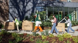 The Duck pushing a speed pak boxing helping new students move into a resident hall