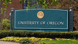 UO sign at entrance of the Eugene campus with yellow flowers in front
