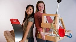 Students holding two prototypes of a cornhole game for Special Olympians
