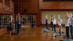 People in a gym doing yoga with an instructor