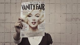 Woman holding magazine cover featuring Marilyn Monroe's face over her own face