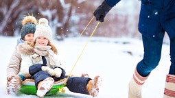 Parent pulling chlidren on a sled in the snow