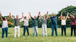 Group of adults of various shapes with arms raised and hands clasped