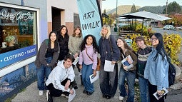 Students posing on sidewalk in front of a business