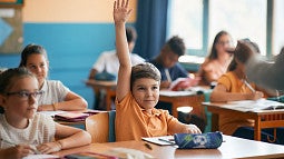 A child raising his hand in class