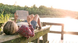 Girl reading by a lake