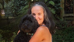 Sousa-Ransford, holding her black Labradoodle Lyra, has come to enjoy canine companionship