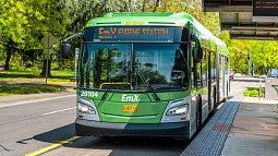A green bus that reads EmX is parked at a station