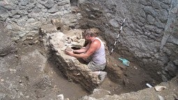 UO classics professor Kevin Dicus examins pottery from a dig in Rome.