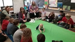 Children and adults watching a baby