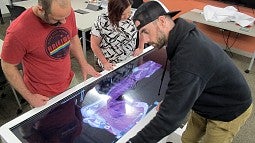 Jon Runyeon, Angie Towle and Mike Stacey look down on the new cadaver table