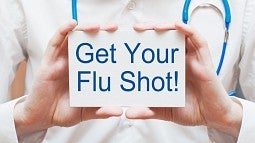 Doctor holding card reading 'Get your flu shot'