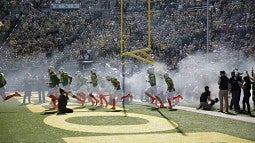 Football players take the field at Autzen Stadium.