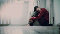 Young man curled up under window