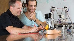 Two men working on a prosthetic foot.