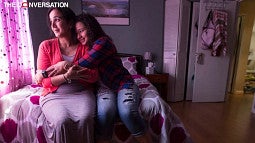Mother and daughter sitting on bed