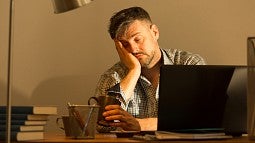 Drowsy man working at laptop