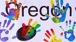 Handprints in paint over word 'Oregon'