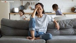 Mother on sofa with kids playing