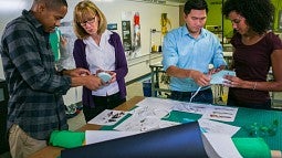 SPM Director Ellen Schmidt-Devlin (second from left) demonstrates footwear-making tools