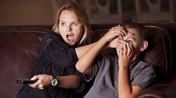 Mom sheilding child's eyes from TV program