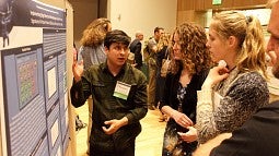 Standing by his poster, Adrian Gutierrez of physics and mathematics tells visitors about his research on strategies to detect particles in experiments at the Large Hadron Collider