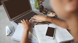 Woman's hands working with laptop, notebooks