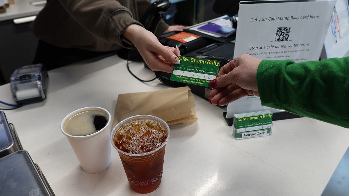 Two people holding coffee punch card at cafe counter