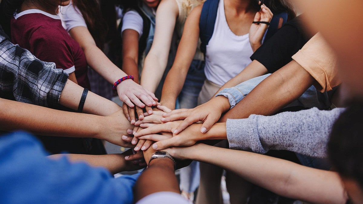 Teens in group with hands extended