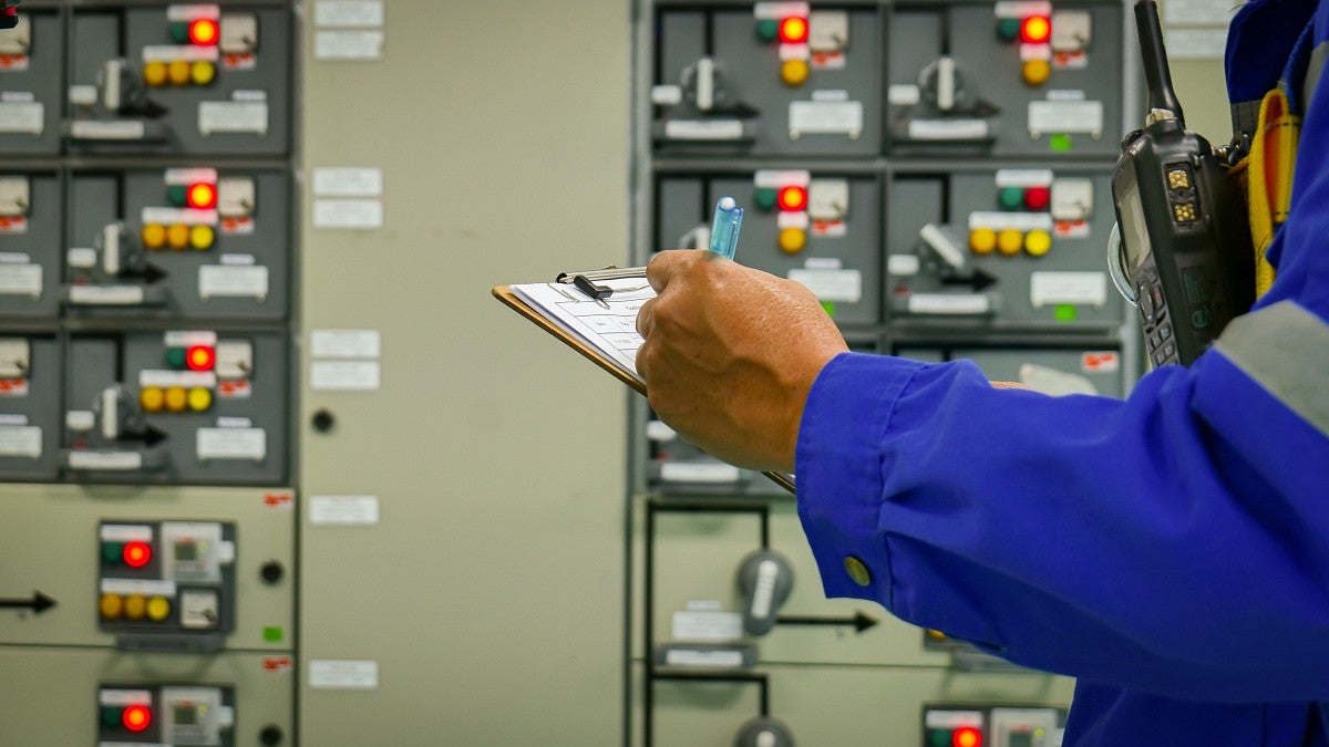 electrical panels with person holding a clipboard and taking notes