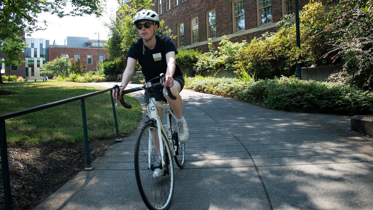 a person rides a white bicycle near the science buildings on the UO campus