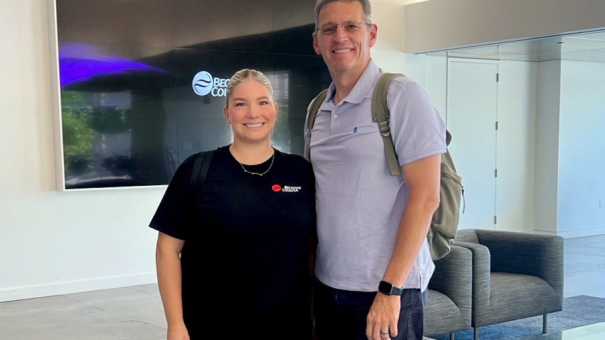 UO intern Lily Kunde with standing with an older male in Beckman Coulter Diagnostics office space.